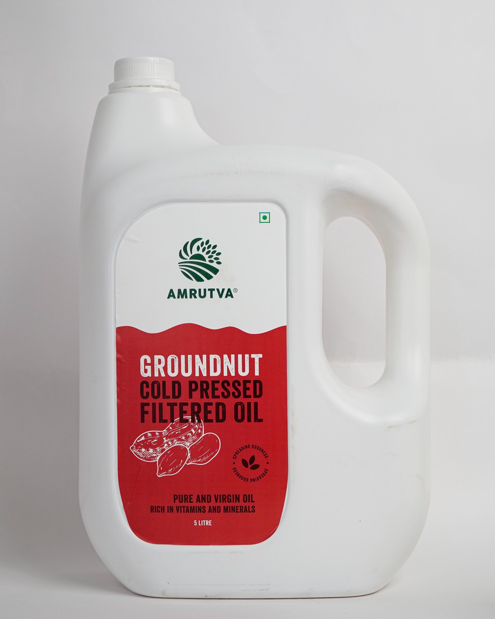 Amrutva Cold Pressed Groundnut Oil - A bottle of groundnut oil beside a bowl of peanuts.