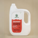 Amrutva Cold Pressed Groundnut Oil - A bottle of groundnut oil beside a bowl of peanuts.