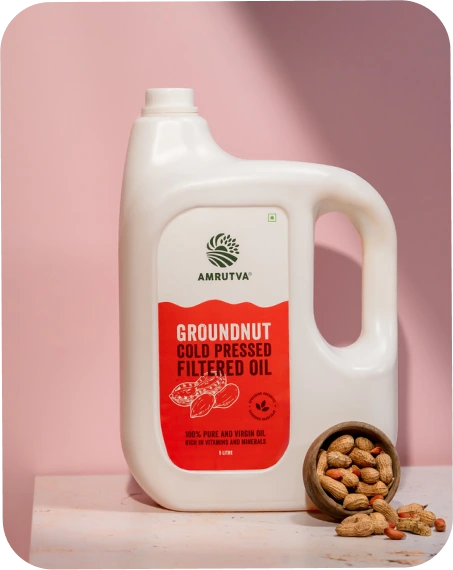 Amrutva Cold Pressed Groundnut Oil - A bottle of groundnut oil beside a bowl of peanuts.