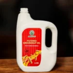 Amrutva Cold Pressed Groundnut Oil - A bottle of groundnut oil beside a bowl of peanuts.