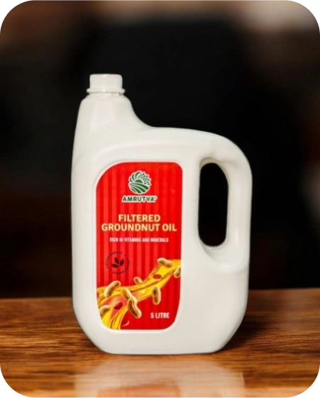 Amrutva Cold Pressed Groundnut Oil - A bottle of groundnut oil beside a bowl of peanuts.