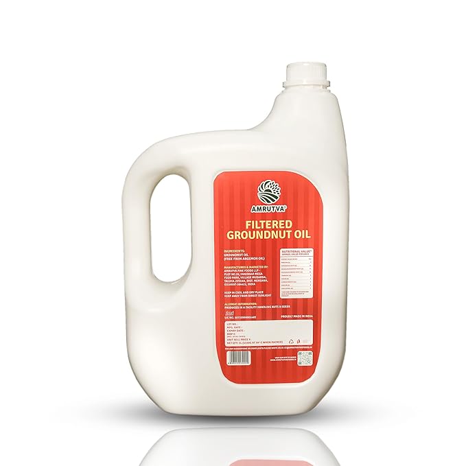 Amrutva Cold Pressed Groundnut Oil - A bottle of groundnut oil beside a bowl of peanuts.