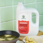 Amrutva Cold Pressed Groundnut Oil - A bottle of groundnut oil beside a bowl of peanuts.
