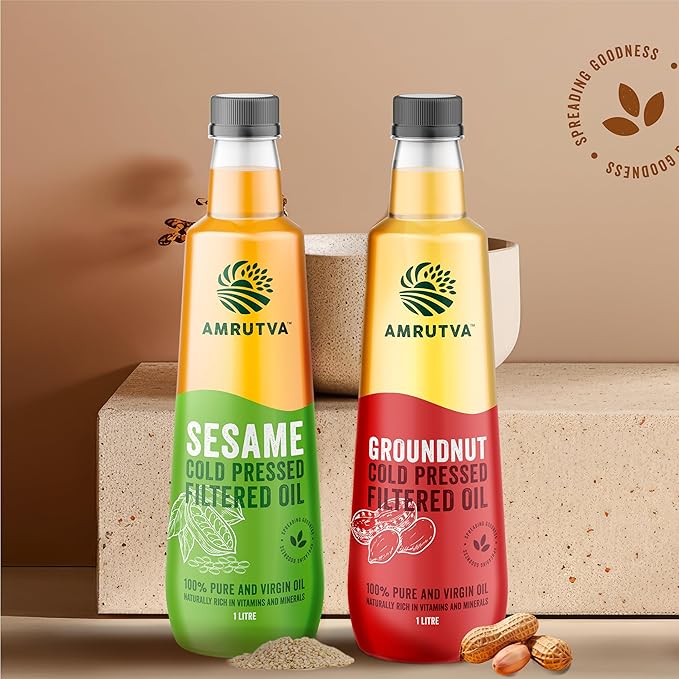 Amrutva Cold Pressed Groundnut and Sesame Oil Combo. This image shows two bottles of cold pressed oil; one groundnut and one sesame; alongside raw ingredients.
