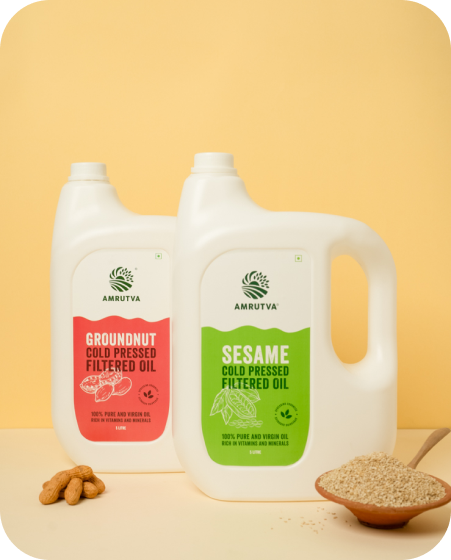 Amrutva Cold Pressed Sesame and Groundnut Oil Combo. This image shows two bottles of cold pressed oil; one sesame and one groundnut; alongside their respective raw ingredients. This combo offer provides a healthy and flavorful option for cooking.