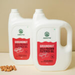 2 pet bottles of cold pressed groundnut oil filtered pack of 2 with some peanuts near the bottle